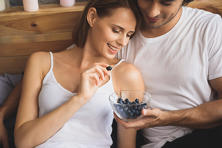 Young Couple Sharing a Bowl of Blueberries